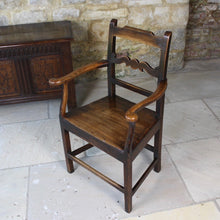 Load image into Gallery viewer, good-colour-early-19th-century-elm-open-armchair-originating-from-north-wales-square-styles-rails-stepped-top-rail-decorative-middle-rail-with-central-roundal-between-two-serpentine-shaped-elements-serpentine-shape-arms-arm-supports-decorative-chair-two-plank-elm-seat-square-legs-united-by-stretchers-wonderful-patina-contrasting-black-golden-honey-colours-particularly-attractive-traditional-contemporary-for-sale-damon-blandford-antiques-stroud-stow-on-the-wold-cotswolds-regional-furniture