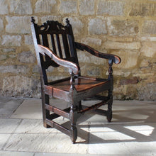 Load image into Gallery viewer, good-late-C17th-English-joined-oak-armchair-slat-back-good-angle-rake-particularly-comfortable-features-highly-decorative-well-carved-crest-rail-shaped-mid-rail-considerable-aesthetic-appeal-down-swept-arms-nicely-turned-supports-boarded-seat-turned-square-legs-stretchers-good-solid-condition-excellent-colour-beautifully-contrasting-black-gold-tones-for-sale-damon-blandford-antiques-stroud-stow-on-the-wold-early-oak-cotswold-country-house