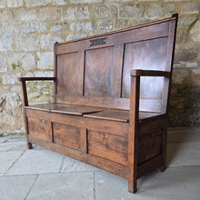 Load image into Gallery viewer, Good-colour-early-19th-century-box-settle-elm-back-rest-with-gentle-rake-three-panels-top-rail-carved-initials-J.I.A.I.-box-storage-section-bench-seat-arm-rests-square-supports-attractive-useful-furniture-hallway-boot-room-welsh-boarders-circa-1800-for-sale-damon-blandford-antiques-stow-on-the-wold-cotswolds
