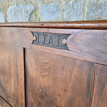 Load image into Gallery viewer, Good-colour-early-19th-century-box-settle-elm-back-rest-with-gentle-rake-three-panels-top-rail-carved-initials-J.I.A.I.-box-storage-section-bench-seat-arm-rests-square-supports-attractive-useful-furniture-hallway-boot-room-welsh-boarders-circa-1800-for-sale-damon-blandford-antiques-stow-on-the-wold-cotswolds