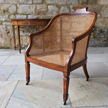 Load image into Gallery viewer, fine-19th-century-adam-style-bergère-arm-chair-generous-wide-deep-proportions-concave-arm-supports-square-tapered-swept-legs-brass-castors-satinwood-frame-painted-neo-classical-design-foliage-flowers-line-decoration-scrolled-crest-rail-young-lady-spaniel-cane-work-seat-back-rest-excellent-original-condition-good-vibrant-colours-excellent-example-aesthetic-appeal-for-sale-damon-blandford-antiques-stow-on-the-wold-cotswolds