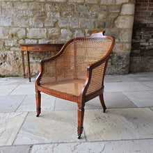 Load image into Gallery viewer, fine-19th-century-adam-style-bergère-arm-chair-generous-wide-deep-proportions-concave-arm-supports-square-tapered-swept-legs-brass-castors-satinwood-frame-painted-neo-classical-design-foliage-flowers-line-decoration-scrolled-crest-rail-young-lady-spaniel-cane-work-seat-back-rest-excellent-original-condition-good-vibrant-colours-excellent-example-aesthetic-appeal-for-sale-damon-blandford-antiques-stow-on-the-wold-cotswolds