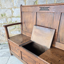 Load image into Gallery viewer, Good-colour-early-19th-century-box-settle-elm-back-rest-with-gentle-rake-three-panels-top-rail-carved-initials-J.I.A.I.-box-storage-section-bench-seat-arm-rests-square-supports-attractive-useful-furniture-hallway-boot-room-welsh-boarders-circa-1800-for-sale-damon-blandford-antiques-stow-on-the-wold-cotswolds