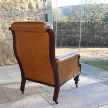Load image into Gallery viewer, super-shape-leather-library-chair-third-quarter-19th-century-gently-reclining-scrolled-backrest-mahogany show-wood-frame-carved-lion-head-details-contrasting-beautifully-light-brown-tobacco-colour-leather-upholstery-sprung-seat-backrest-raised-well-proportioned-square-swept-legs-rear-turned-carved-legs-front-original-brass-cup-castors-porcelain-wheels-chair-real-presence-grandeur-damon-blandford-antiques-seating-upholstery-gloucestershire-cotswolds-interior-style-decoration-decorative-country-house-for-sale