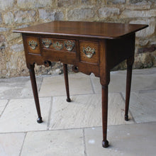 Load image into Gallery viewer, nicely-made-18th-century-provincial-oak-lowboy-three-oak-lined-drawers-cock-beading-original-brass-swan-neck-handles-pierced-back-plates-drawers-decoratively-carved-apron-a-particular-feature-of-this-tableall-raised-on-round-tapering-legs-pad-feet-excellent-colour-condition-north-england-1770-for-sale-damon-blandford-antiques-stroud-gloucestershire-country-house-furniture