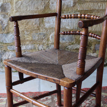 Load image into Gallery viewer, early-19th-century-rush-seated-open-armchair-excellent-quality-combining-carved-turned-details-shaped-bobbin-carved-mid-rails-shaped-top-rail-circular-styles-wonderfully-shaped-arm-rests-ring-turned-arm-supports-rush-seat-very-comfortable-chair-faux-bamboo-legs-stretchers-excellent-quality-condition-english-circa-1850s-for-sale-damon-blandford-antiques-stow-on-the-wold-stroud-cotswolds-gloucestershire-oxfordshire-interior-decor