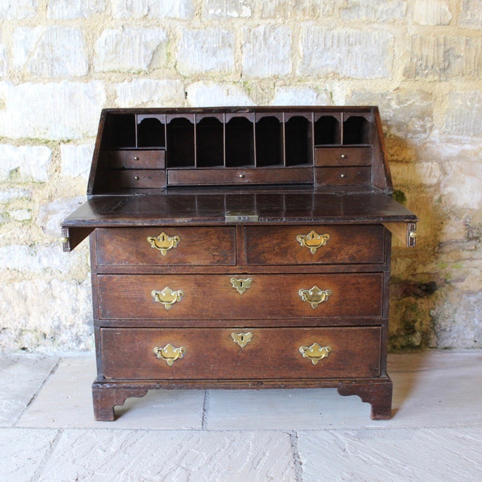 good-quality-18th-century-bureau-constructed-in-oak-fall-front-supported-by-two lopers-bearers-fitted-interior-nine-pigeon-holes-five-small-drawers-concealed-storage-well-two-short-two-long-drawers-dovetail-construction-brass-drop-handles-bracket-feet-highly-original-regional-furniture-excellent-condition-good-colour.-for-sale-damon-blandford-antiques-stow-on-the-wold-cotswolds-antique-strorage