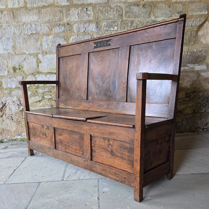Good-colour-early-19th-century-box-settle-elm-back-rest-with-gentle-rake-three-panels-top-rail-carved-initials-J.I.A.I.-box-storage-section-bench-seat-arm-rests-square-supports-attractive-useful-furniture-hallway-boot-room-welsh-boarders-circa-1800-for-sale-damon-blandford-antiques-stow-on-the-wold-cotswolds
