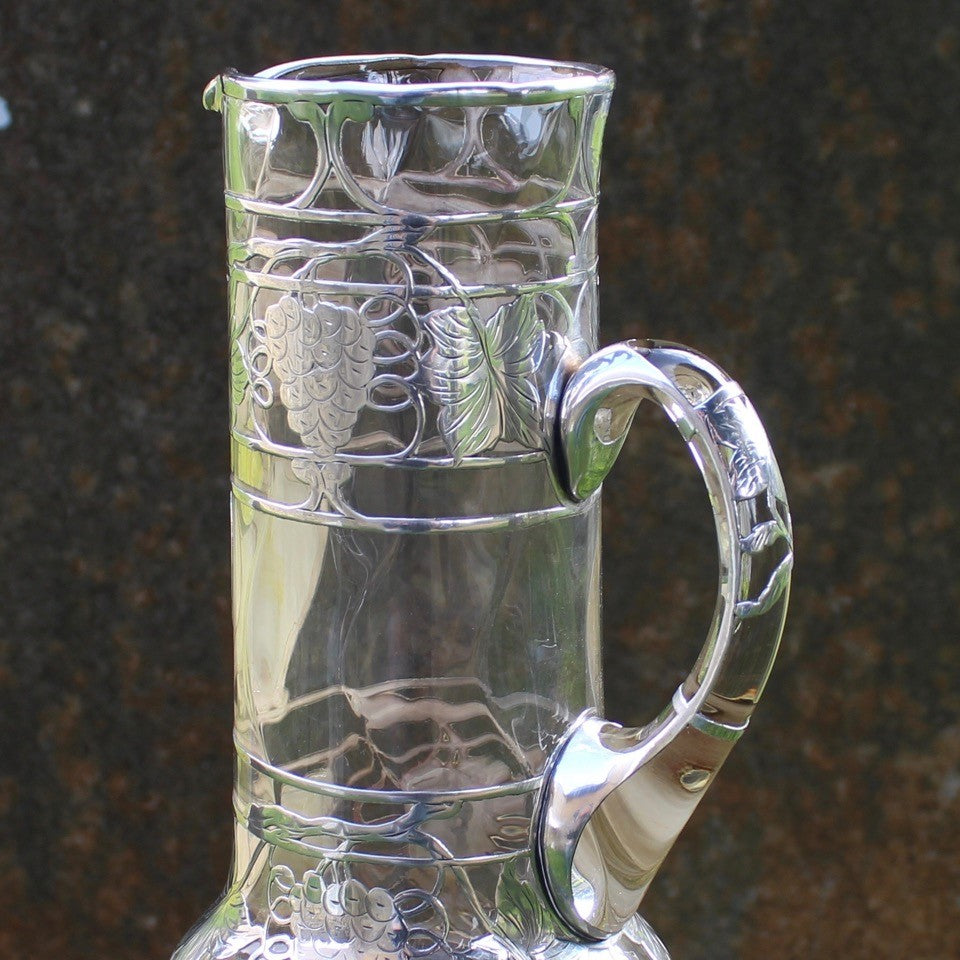 attractive-american-art-nouveau-riven-glass-claret-jug-silver-overlay-jug-cylindrical-form-small-lipped-spout-spread-base-c-scroll-handle-silver-overlay-intricate-design-featuring-grapes-vine-leaves-heart-shape-cartouche-exceptionally-good-quality-excellent-condition-turn-of-19th-20th-century-for-sale-damon-blandford-antiques-stroud-gloucestershire-cotswolds