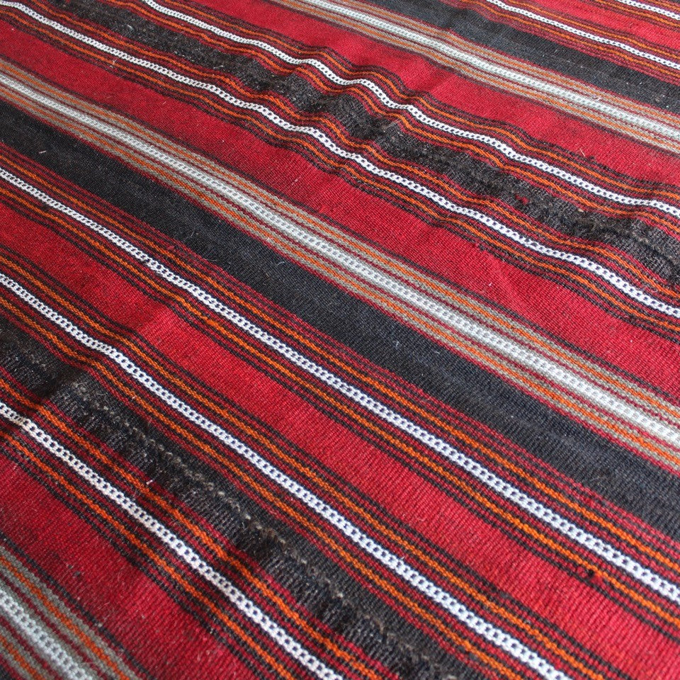 attractive-flatweave-kilim-striped-design-predominantly-shades-red-orange-brown-white-grey-rug-five-long-narrow-lengths-carefully-sewn-together-kilim-nomadic-tribe-camel-table-rug-sitting-floor-communal-bowl-food-good-hard-wearing-kilim-stylish-picnic-rug-turkish-for-sale-damon-blandford-antiques-vintage-kilims-carpets-rugs-stroud-stow-on-the-wold-cotswolds-interiors-design